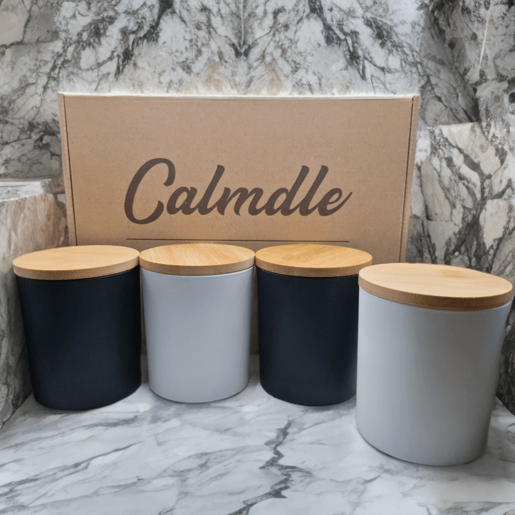 Set Complet De Bougies Parfumees Calmdle avec quatre bougies parfumees dans des contenants noirs et blancs et des couvercles en bois
